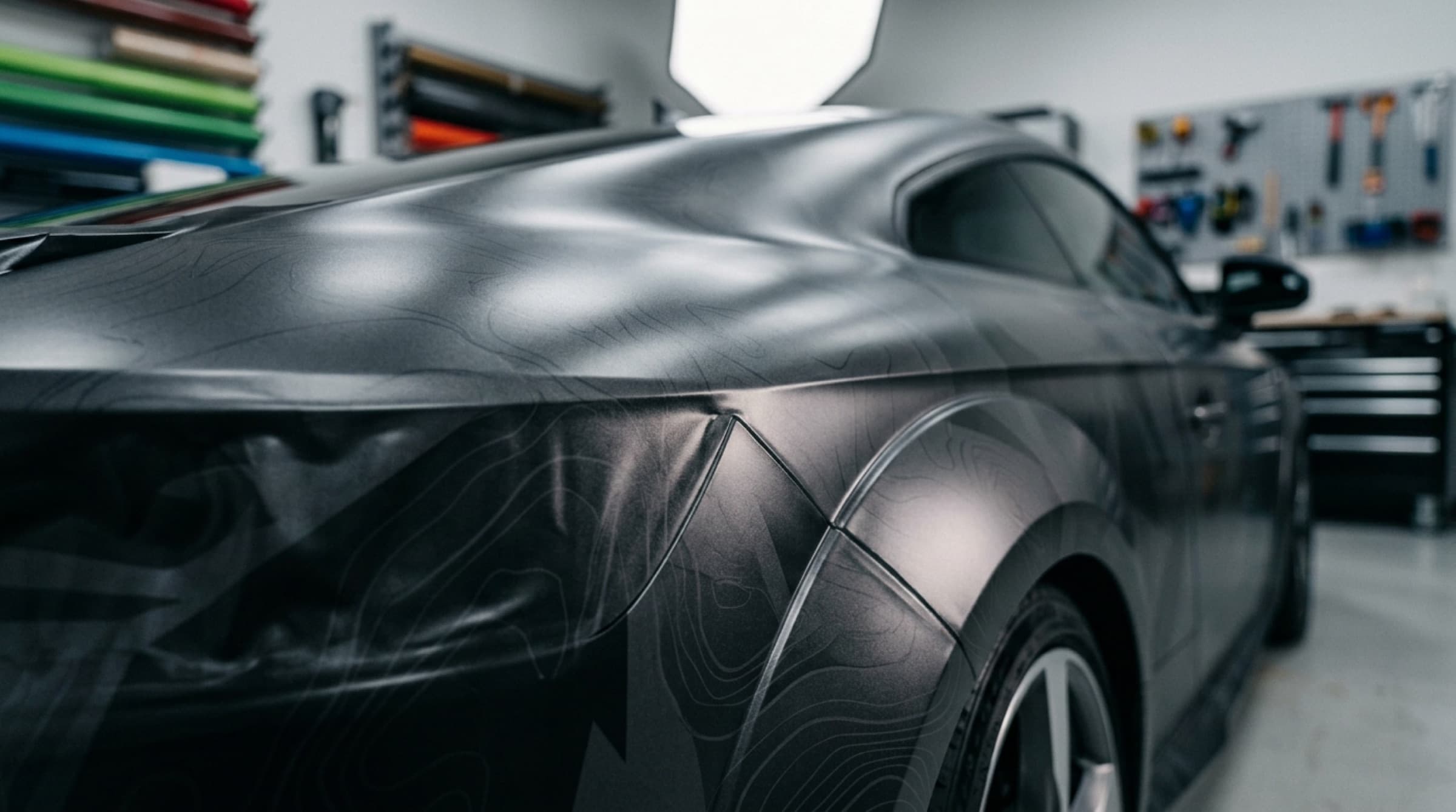 Macro detail of a matte vehicle wrap with vinyl swatches in the background